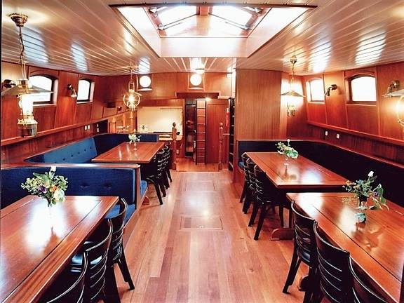 Salon van de Poseidon met houten eettafels en blauwe zitbanken