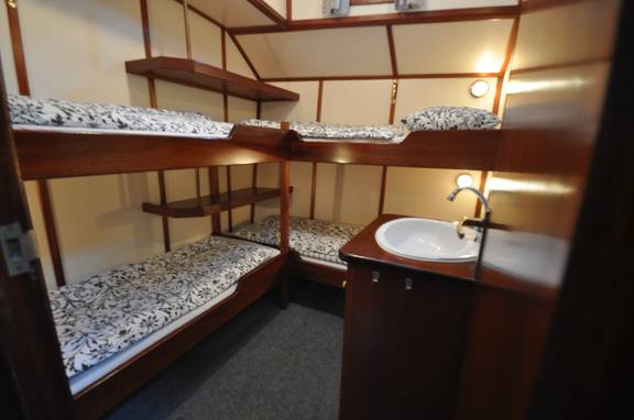 Hut met stapelbedden en wastafel op de Poseidon