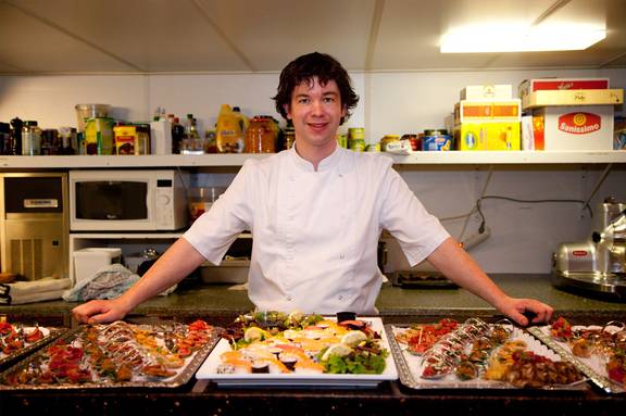Kok bij schalen met gerechten in de keuken van de Smaragd 1