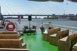Houten banken op het groene dek van de Smaragd 1 met uitzicht op de Erasmusbrug