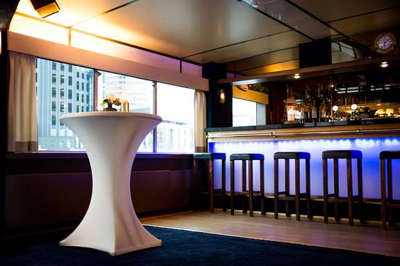 Bar met blauwe verlichting en barkrukken in de salon van de Smaragd 2