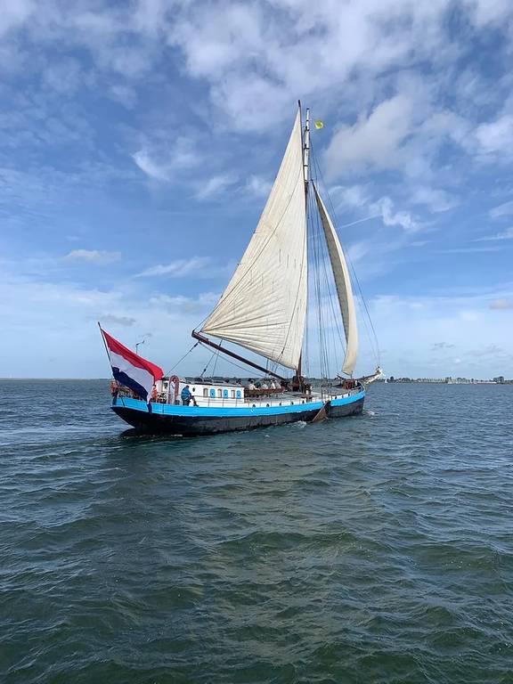 Spartivento met wit zeil en Nederlandse vlag op open water