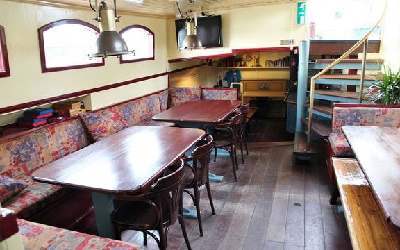 Dagverblijf van de Sybaris met houten eettafels en zitbanken