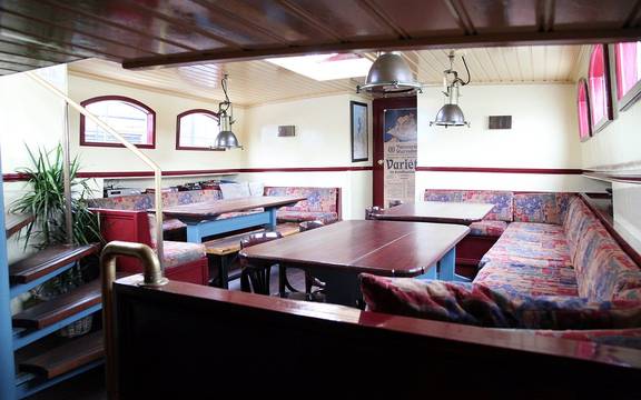 Dagverblijf van de Sybaris met houten eettafels en zitbanken
