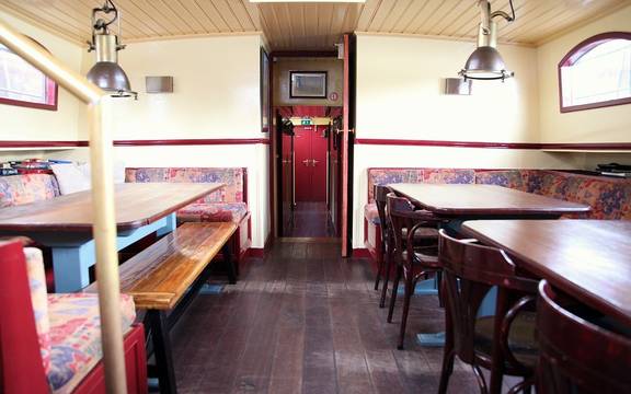 Dagverblijf van de Sybaris met houten eettafels en zitbanken