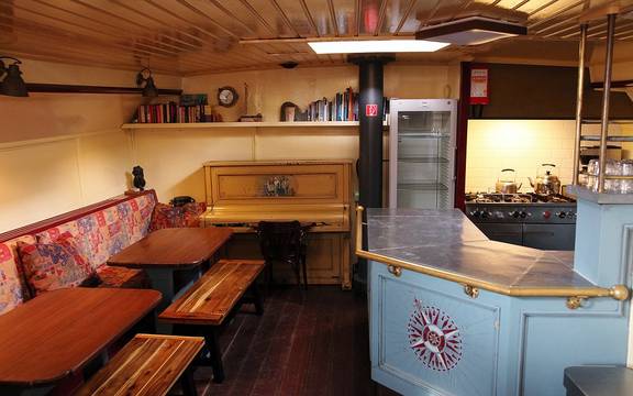 Houten eettafel en zitbanken naast de kombuis van de Sybaris