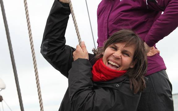 Jonge gast helpt een zeil hijsen op de Sybaris