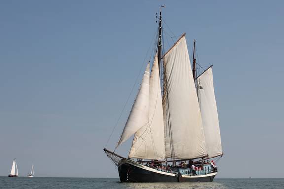 Klipper Sybaris onder witte zeilen op het water