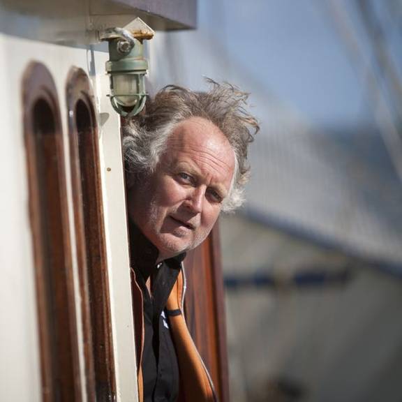 Kapitein Jacob Jan Dam kijkt uit de deuropening van de Thalassa