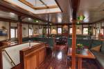 Houten salon van de Thalassa met tafels en groene zitbanken