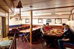 Gasten aan de eettafels in de houten salon van de Thalassa