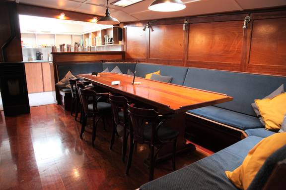 Salon van de Vrijheid met houten eettafels en zitbanken