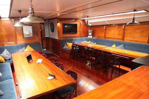 Salon van de Vrijheid met houten eettafels en zitbanken