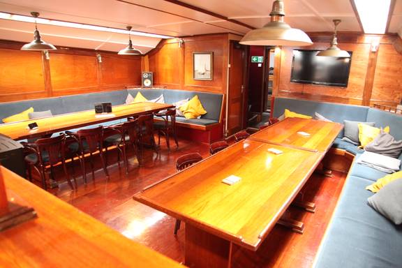 Salon van de Vrijheid met houten eettafels en zitbanken