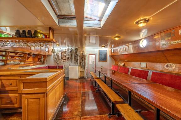 Houten salon van de Waterman met eettafels en rode zitbanken