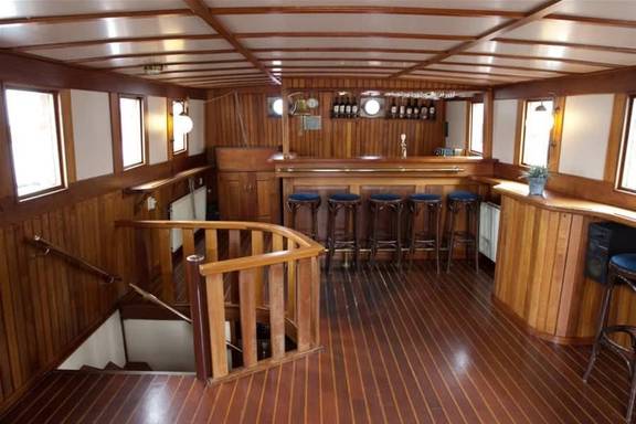 Houten dekhuis met tafels en stoelen op de Willem Barentsz