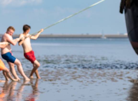 Scholieren op het drooggevallen Wad naast een zeilschip