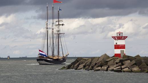 Tallship vaart langs een rood-wit havenlicht