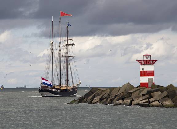 Tallship vaart langs een rood-wit havenlicht