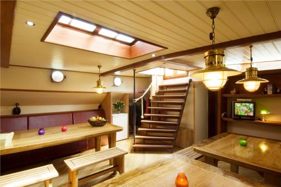 Salon van de Gulden Belofte met houten eettafels en zitbanken