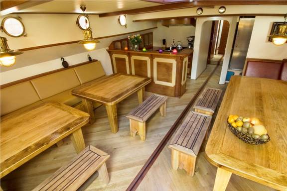 Salon van de Gulden Belofte met houten eettafels en zitbanken