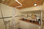 Badkamer van De Lis met wastafel en douche onder een houten plafond
