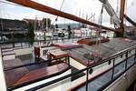 Zitbanken en houten tafel aan dek van De Lis