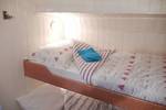 Stapelbed met gestreept beddengoed in een hut van De Lis