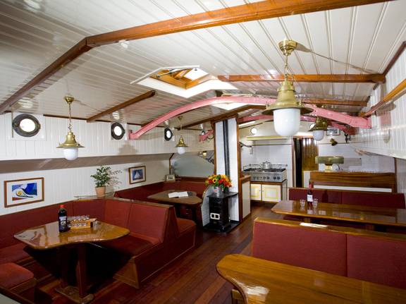 Salon van De Lis met houten tafels en rode zitbanken