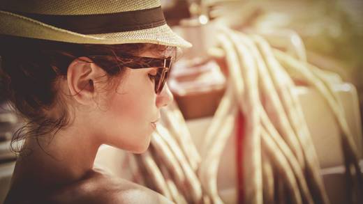 Vrouw met hoed en zonnebril ontspant in de zon