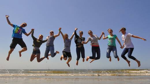 Groep jongeren springt tegelijk omhoog op het strand
