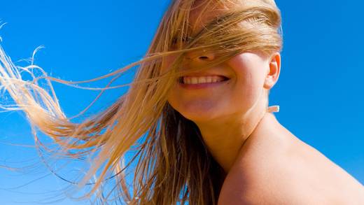 Jonge vrouw met wapperend haar tegen een blauwe lucht