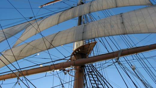 Uitzicht omhoog langs mast en witte ra-zeilen van een tallship