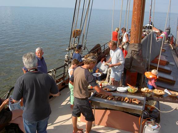 Gasten barbecueën aan dek van de Albatros tijdens het droogvallen op het Wad