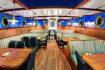 Eetzaal met houten tafels en patrijspoorten op de Mare fan Fryslân