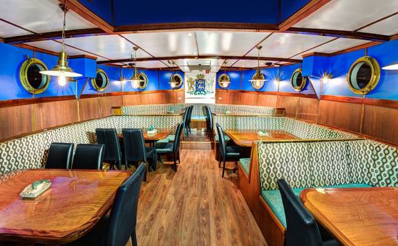 Eetzaal met houten tafels en patrijspoorten op de Mare fan Fryslân