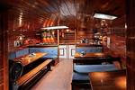 Houten salon van de Orion met eettafels en blauwe zitbanken