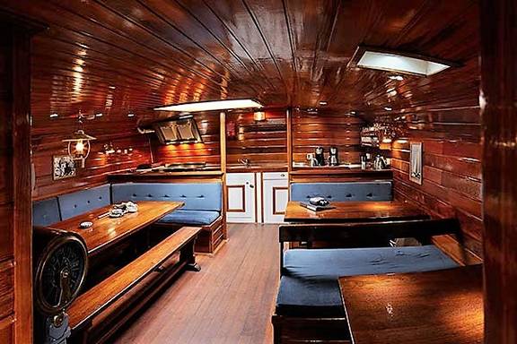 Houten salon van de Orion met eettafels en blauwe zitbanken