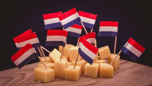 Blokjes kaas met Nederlandse vlaggetjes op een houten plank